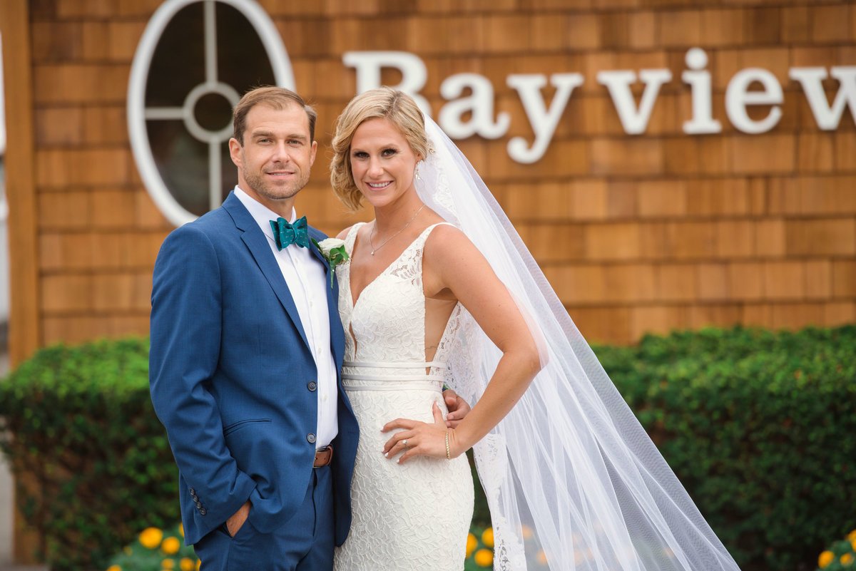 Bride and groom smiling in front of Bayview House sign at Captain Bills