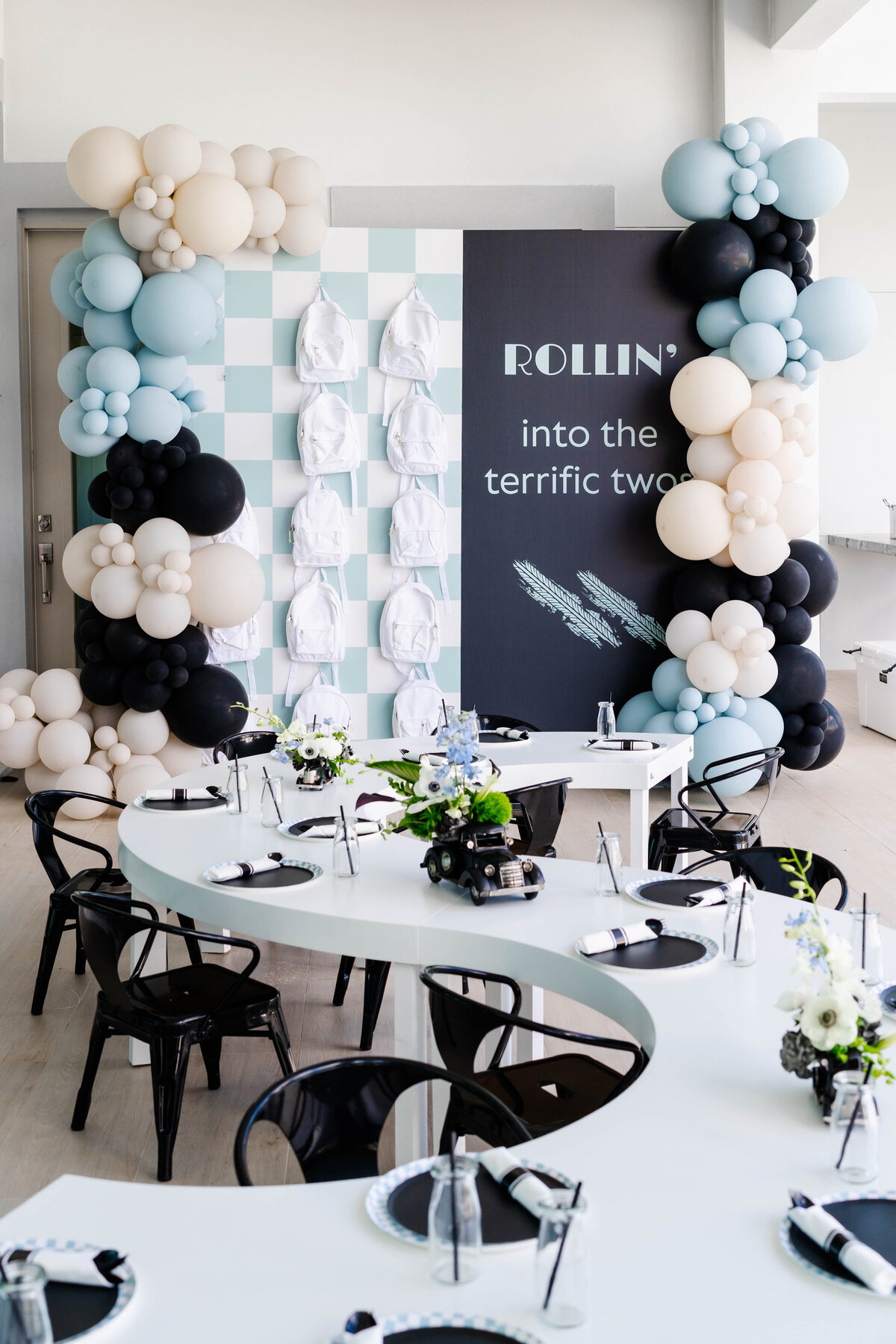 serpentine kids table with black metal chairs and checkered swag backpack wall