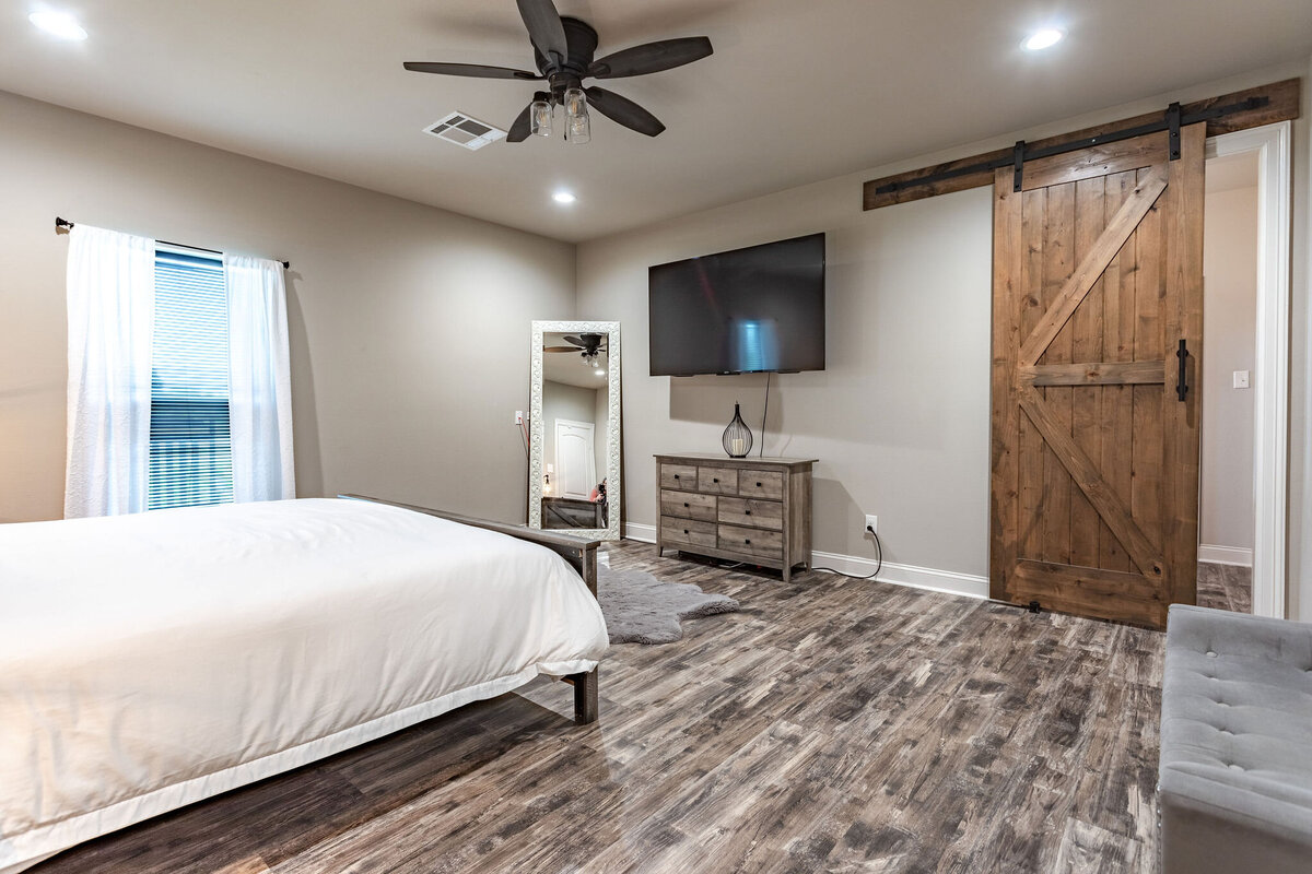 Bedroom with comfortable bedding and smart TV in this five-bedroom, 3-bathroom vacation rental house for up to 10 guests with free wifi, private parking, outdoor games and seating, and bbq grill on 2 acres of land near Waco, TX.