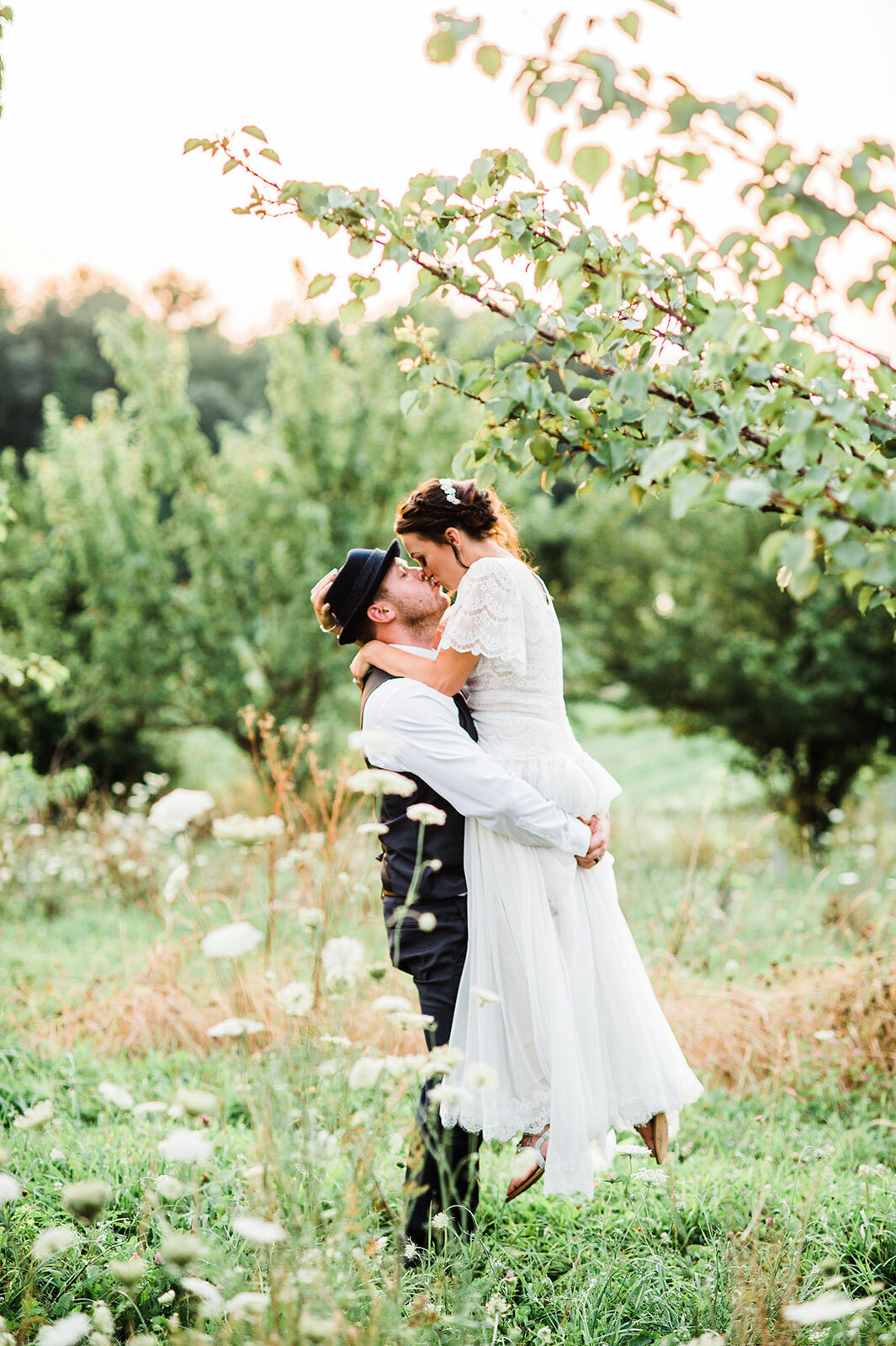 bride and groom kissing in apple orchard at sunset vermont adventure elopement