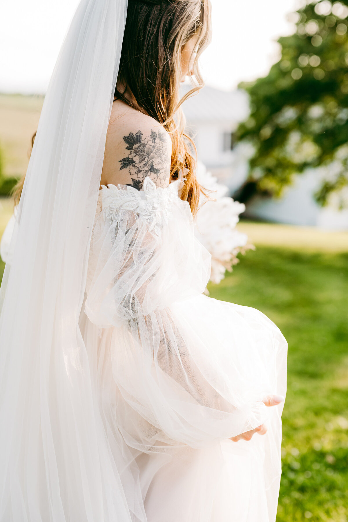 bride with a floral tattoo on her shoulder  wears an off the shoulder wedding dress as she runs through Charlottesville wedding venues lawn
