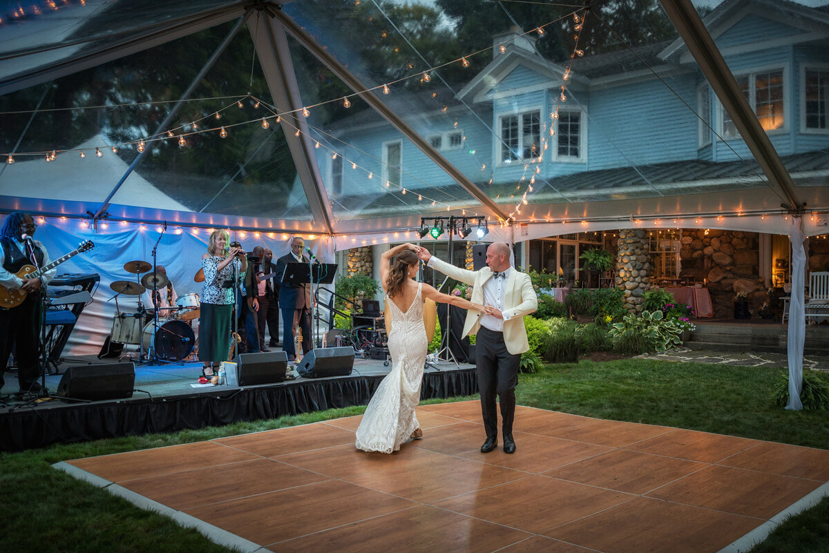 Wedding couple dances in front of band at reception.