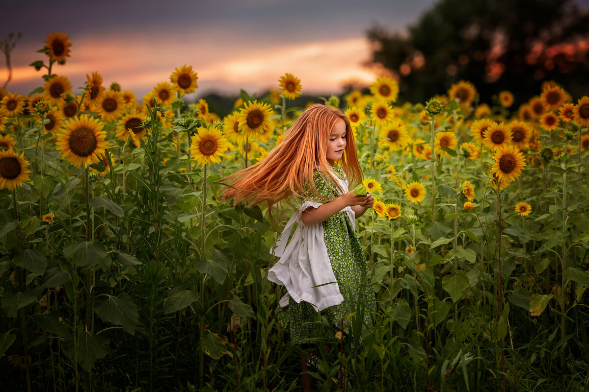 ginger girl in green vintage dress is dancing and spinning in sunflower field.