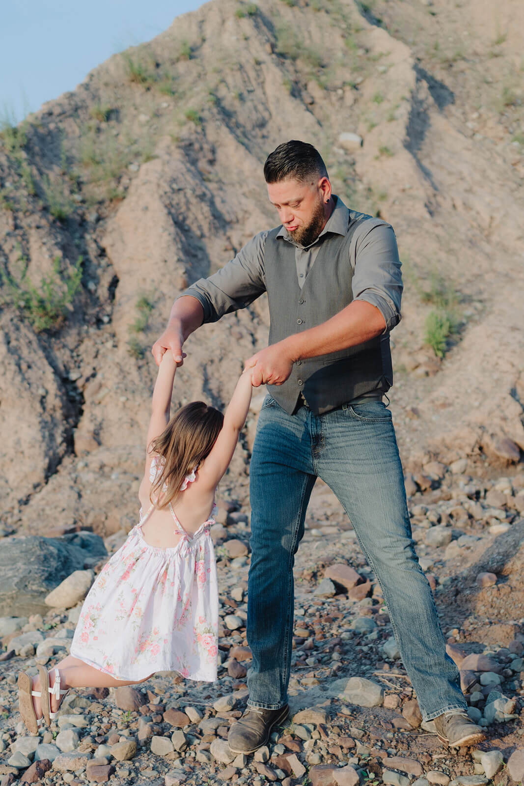 Dad swinging young daughter around at family with two kids on the beach at family photo shoot in Finger Lakes, NY