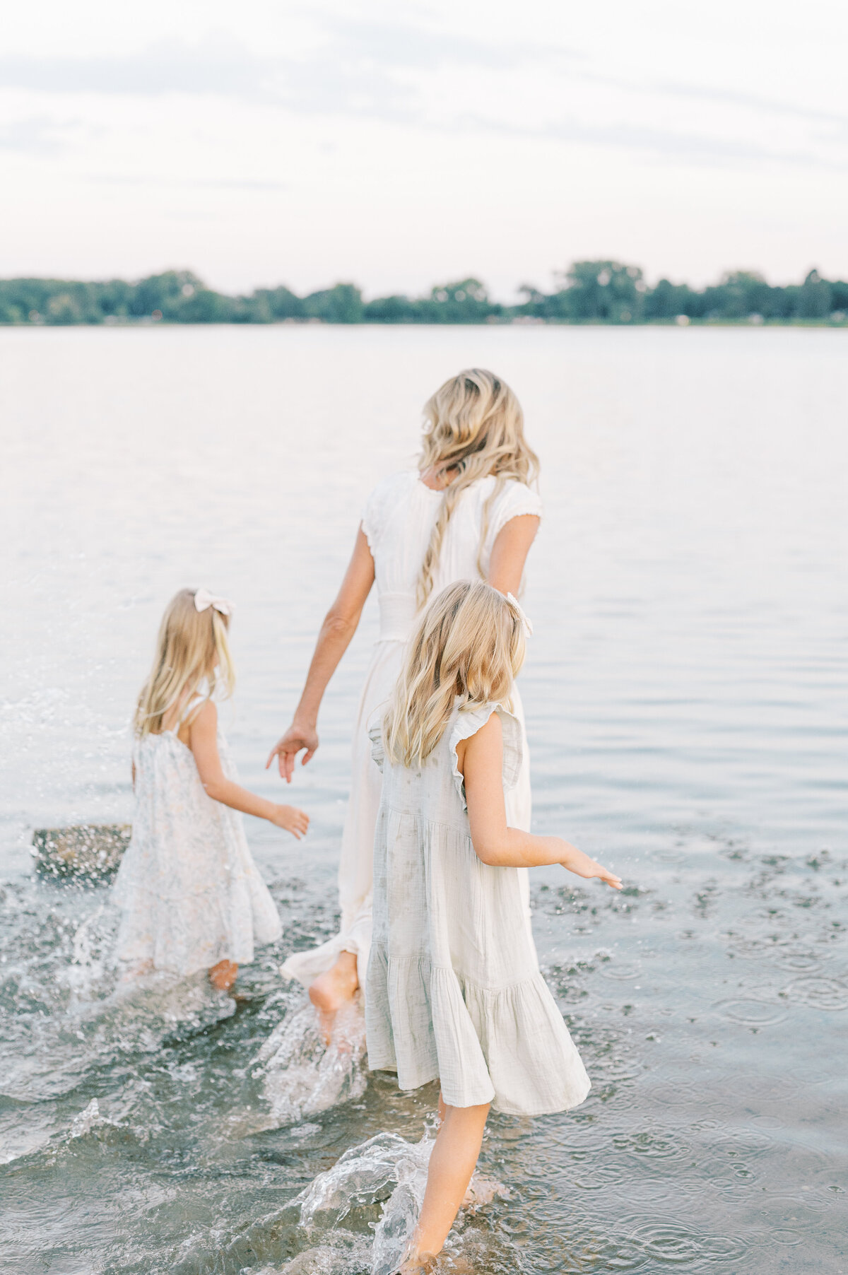 Mom walking with daughters into lake hand in hand