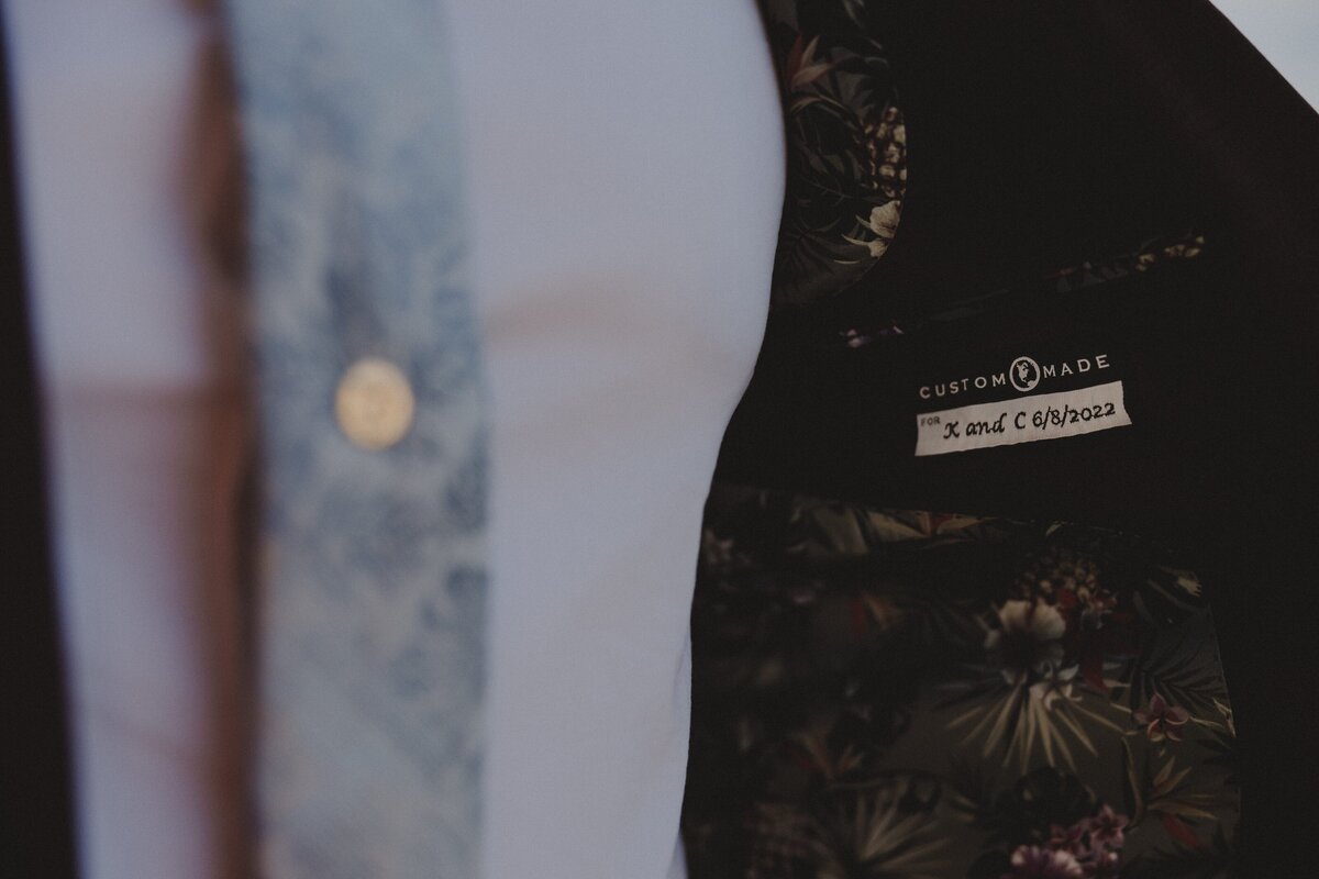 A groom shows off his custom suit on his wedding day, complete with a sewn in tag with their wedding date and initials