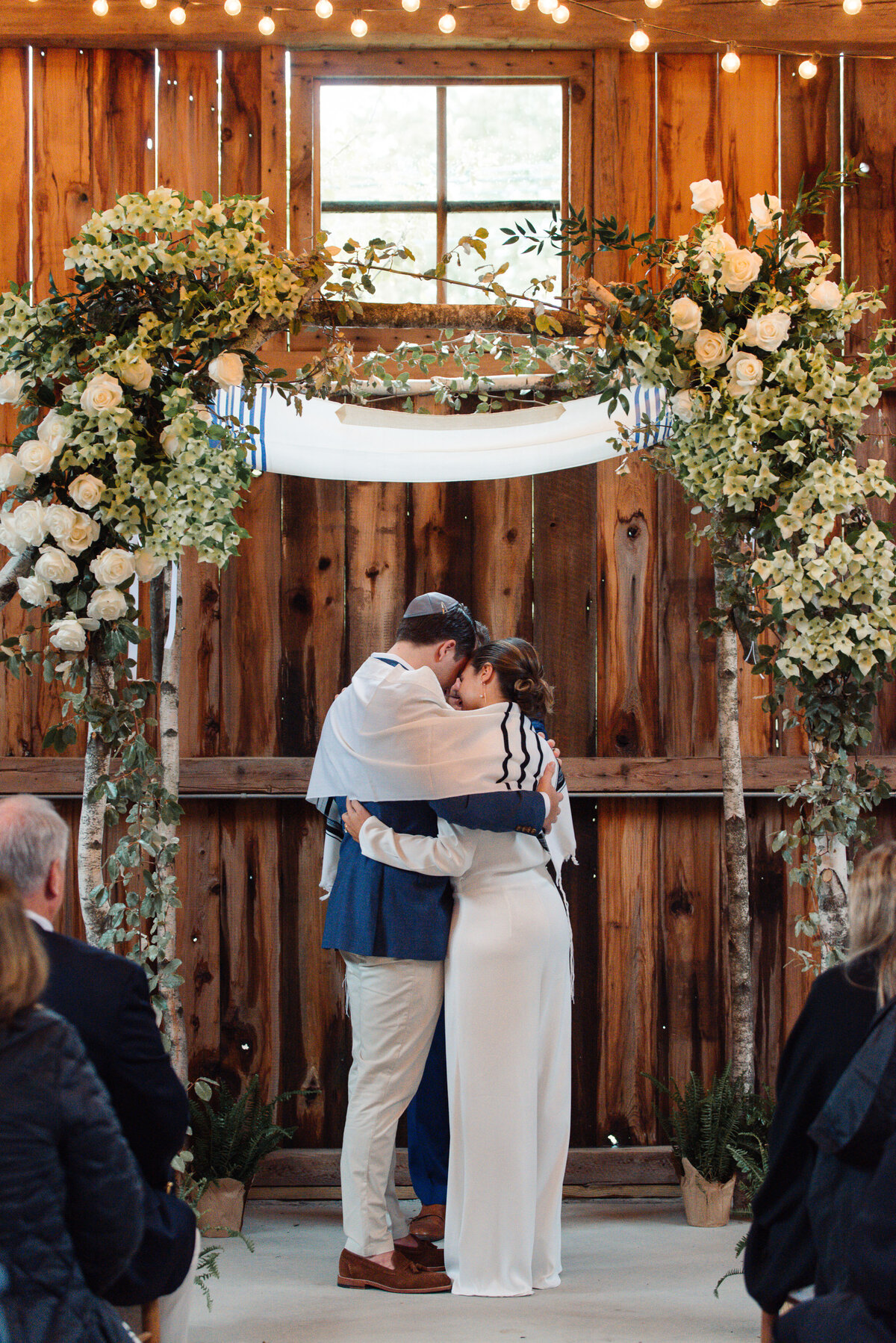Couple stands under huppah designed by Flowers and Flowers by Adam in a historic barn in Norwalk, CT.