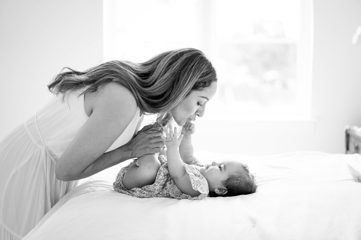 Mother and baby in black in white playing on bed