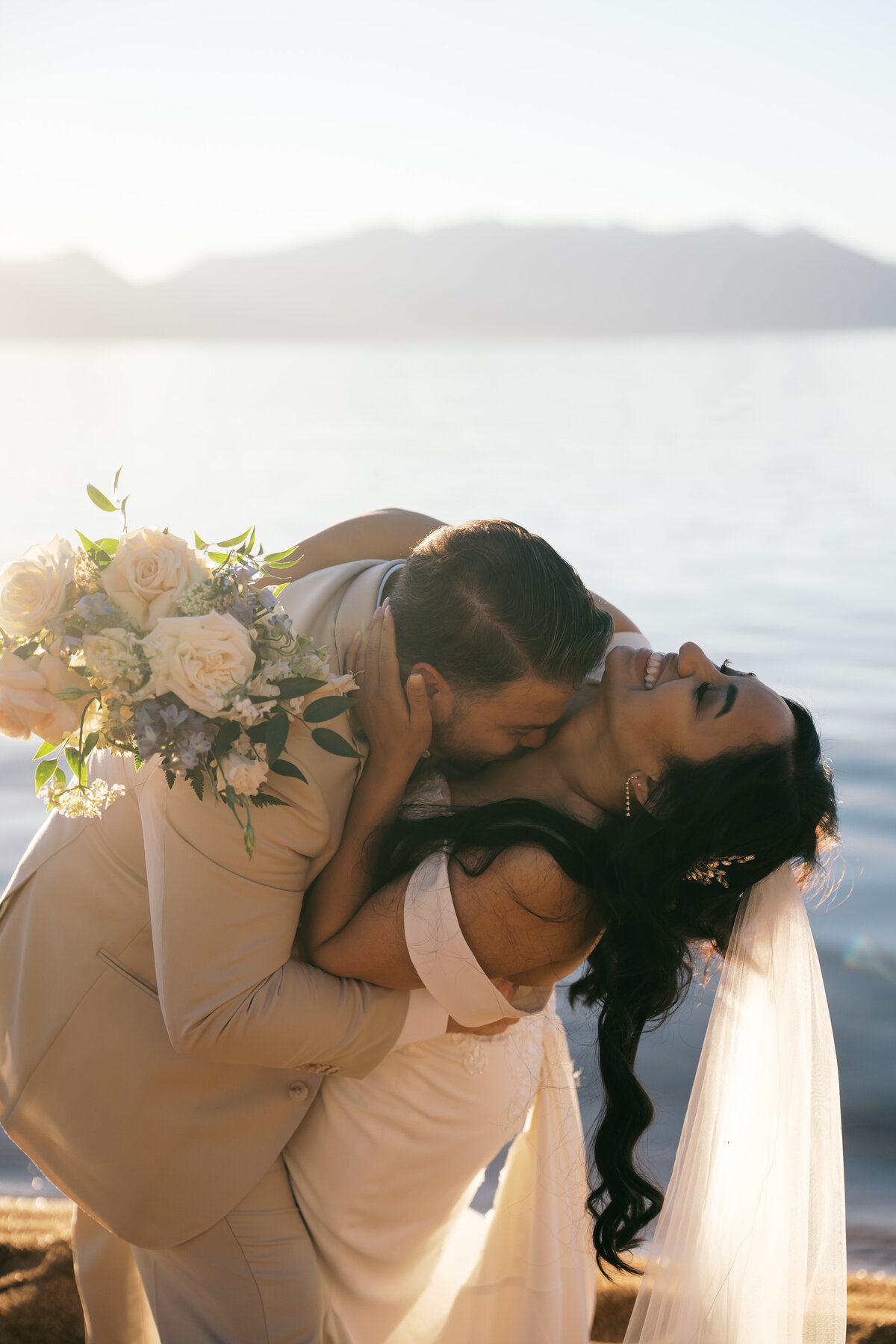 blurry photo of bride and groom hugging, bride is carrying her dress