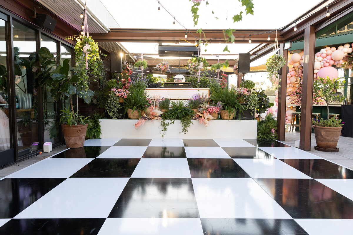 A checkerboard dance floor with plants hanging around it