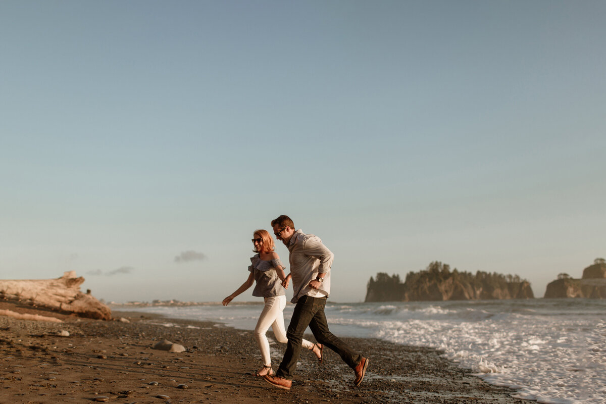 A couple runs on a PNW beach during their summer engagement session captured by Fort Worth Wedding Photographer, Megan Christine Studio
