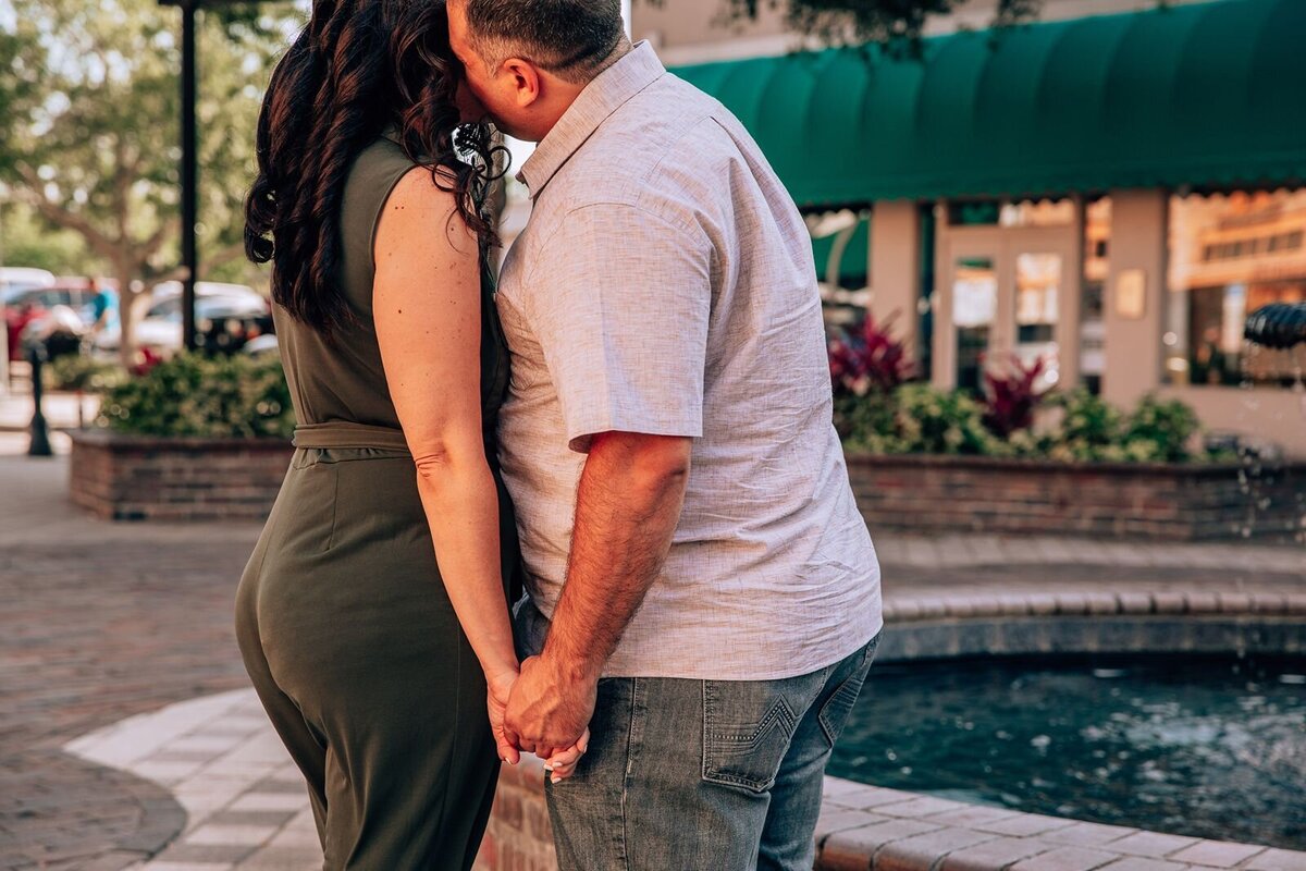 groom kisses brides cheek in front of a fountain in sanford florida