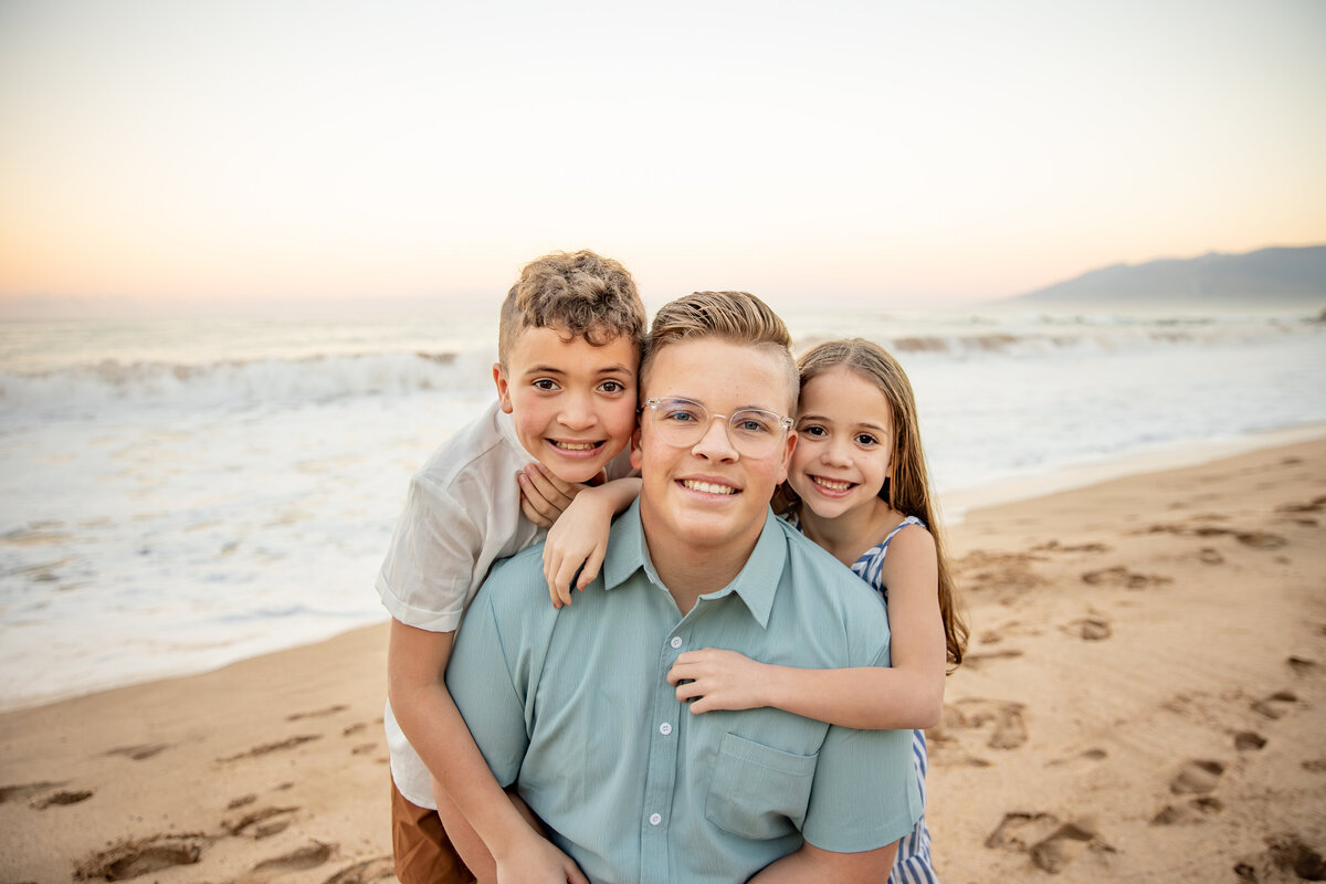 Maui Family Photographers capture children hugging on beach during family beach photos