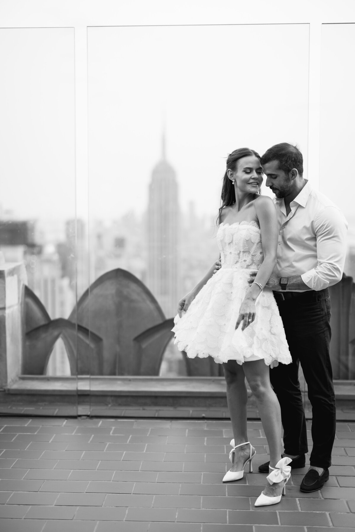 Newlyweds pose on Top of the Rock with the iconic cityscape of New York City, celebrating their love with sweeping views from Rockefeller Center.