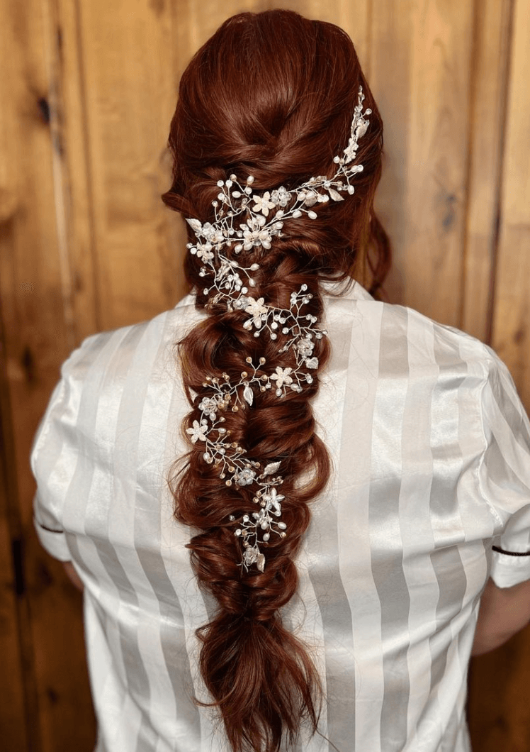 Intricate bridal braid with floral hairpiece showcasing dimensional color by a San Antonio hair color salon and bridal hairdresser