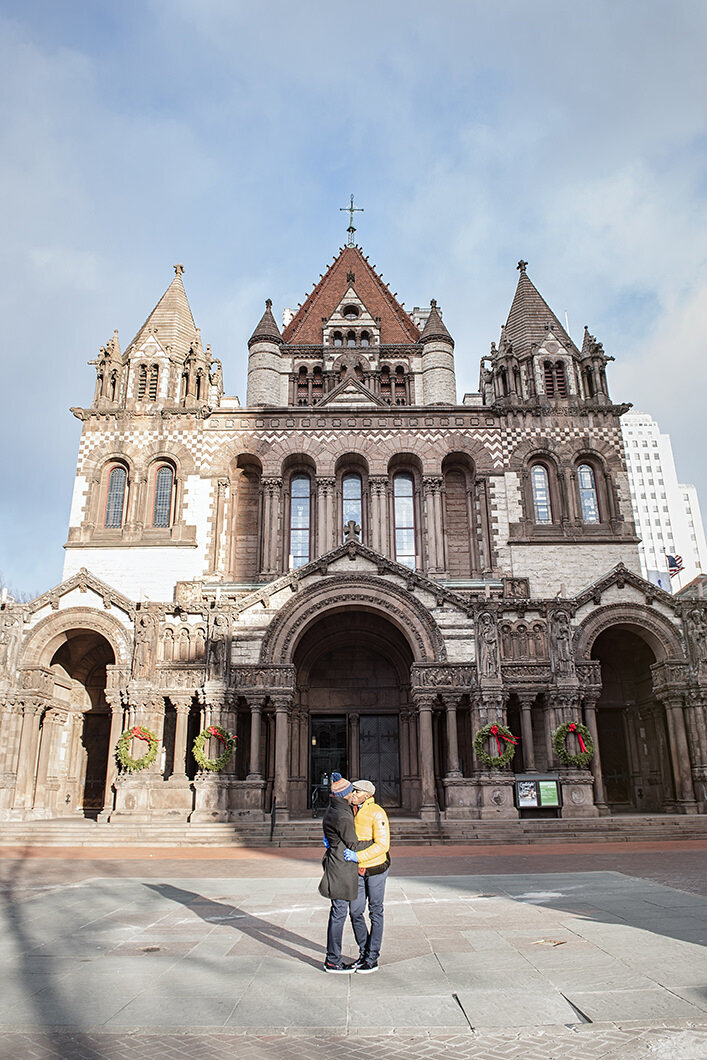 A couple kissing in front of a grand church