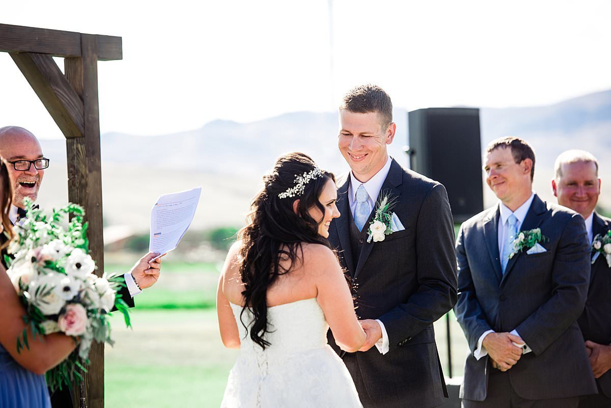 Bright sunny Montana day, husband looking at his wife during their vow exchange as she smiles at her parents
