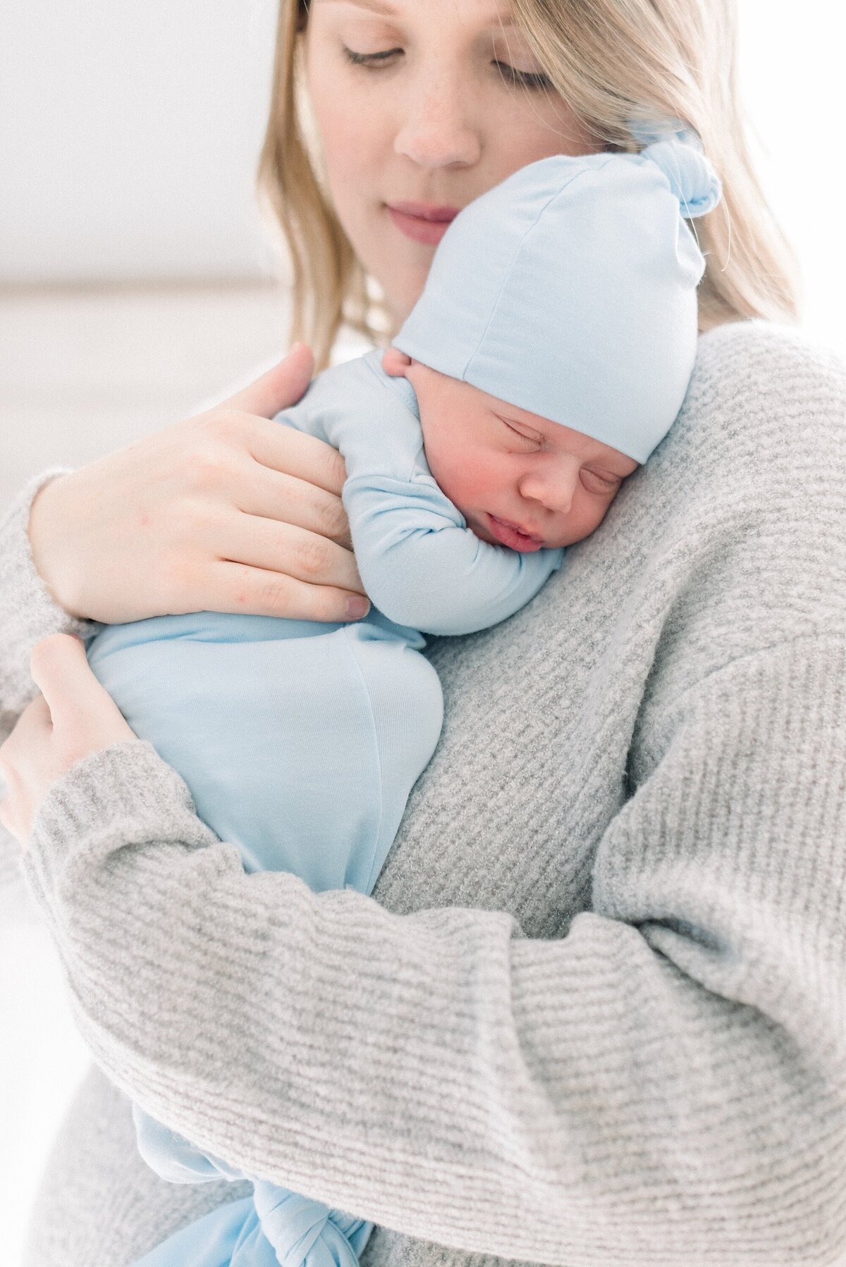 mom holding newborn baby boy in blue swaddle