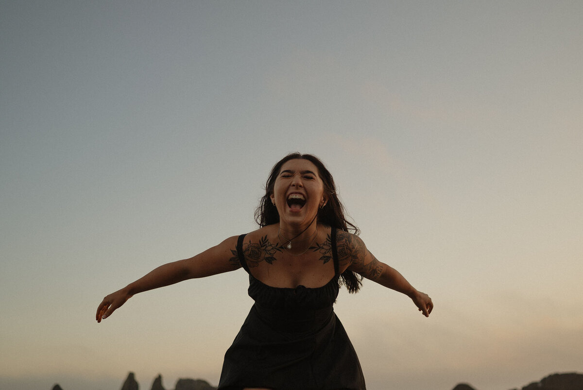 woman yells and expresses her joy at the Oregon Coast