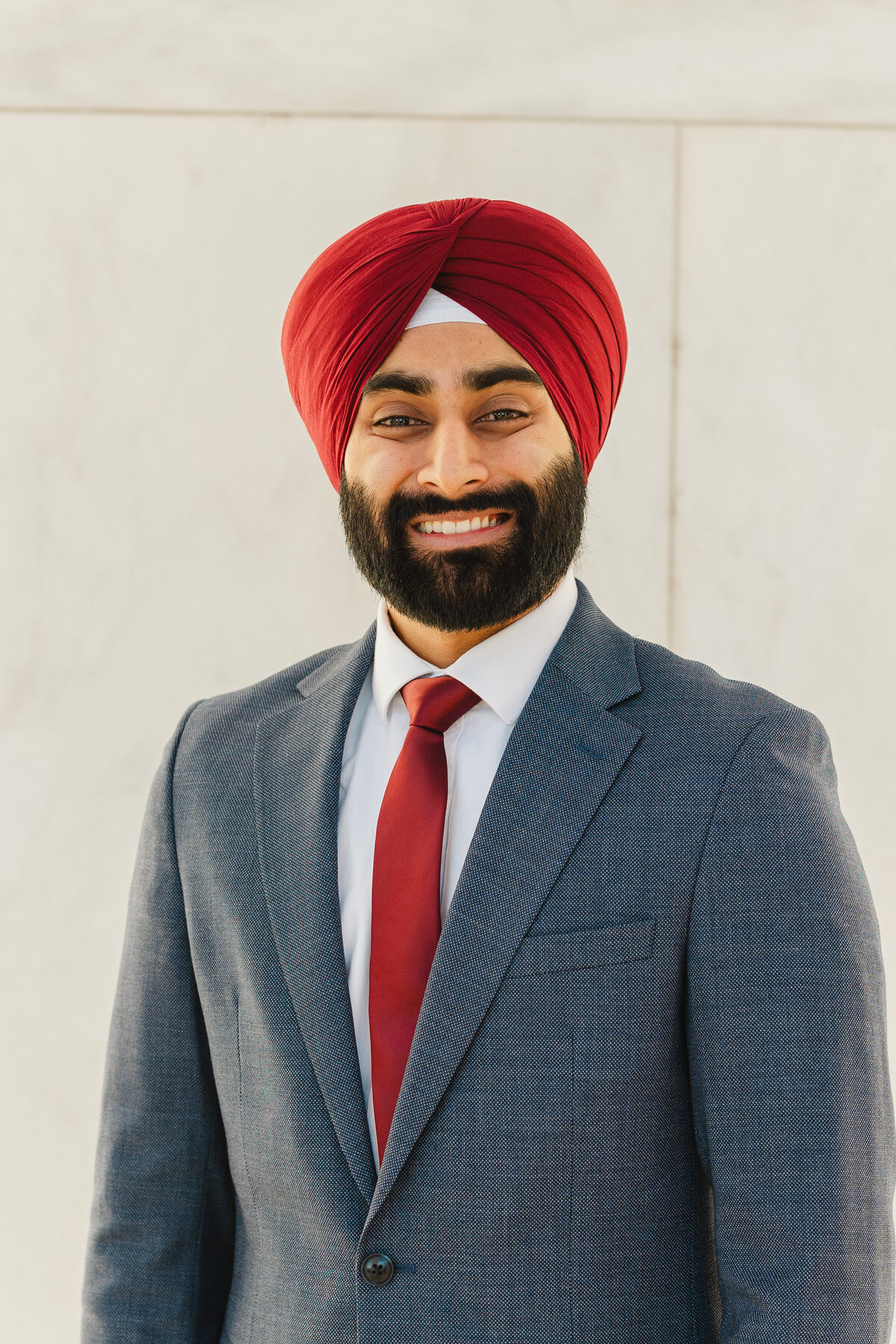 A person smiles in front of a white wall.