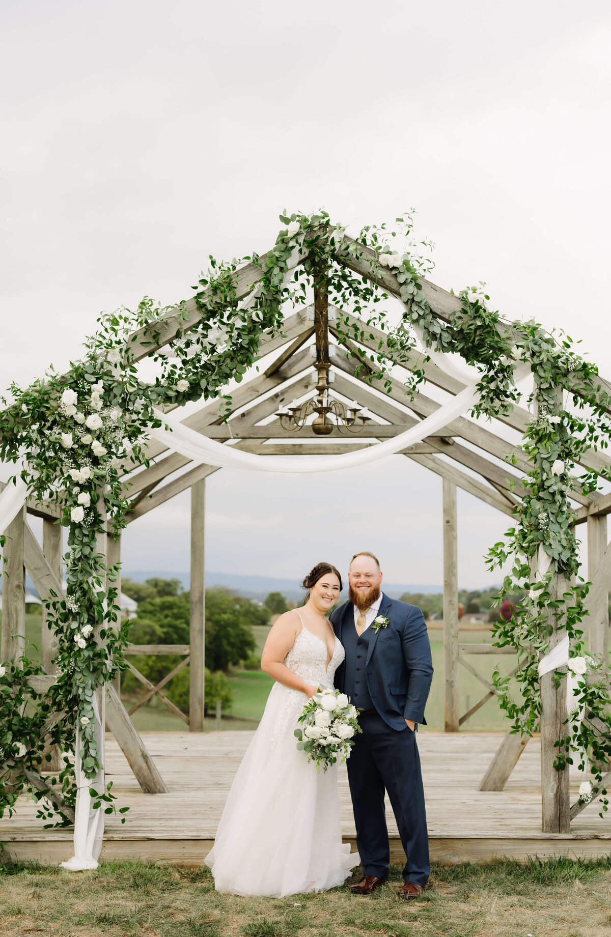 Shenandoah National Park wedding with luxury floral arrangements on a wood frame of a house with bride and groom posing for a portrait together