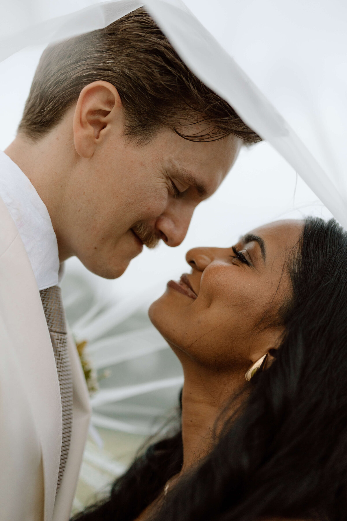 A close up photo of a couple about to kiss on their wedding day