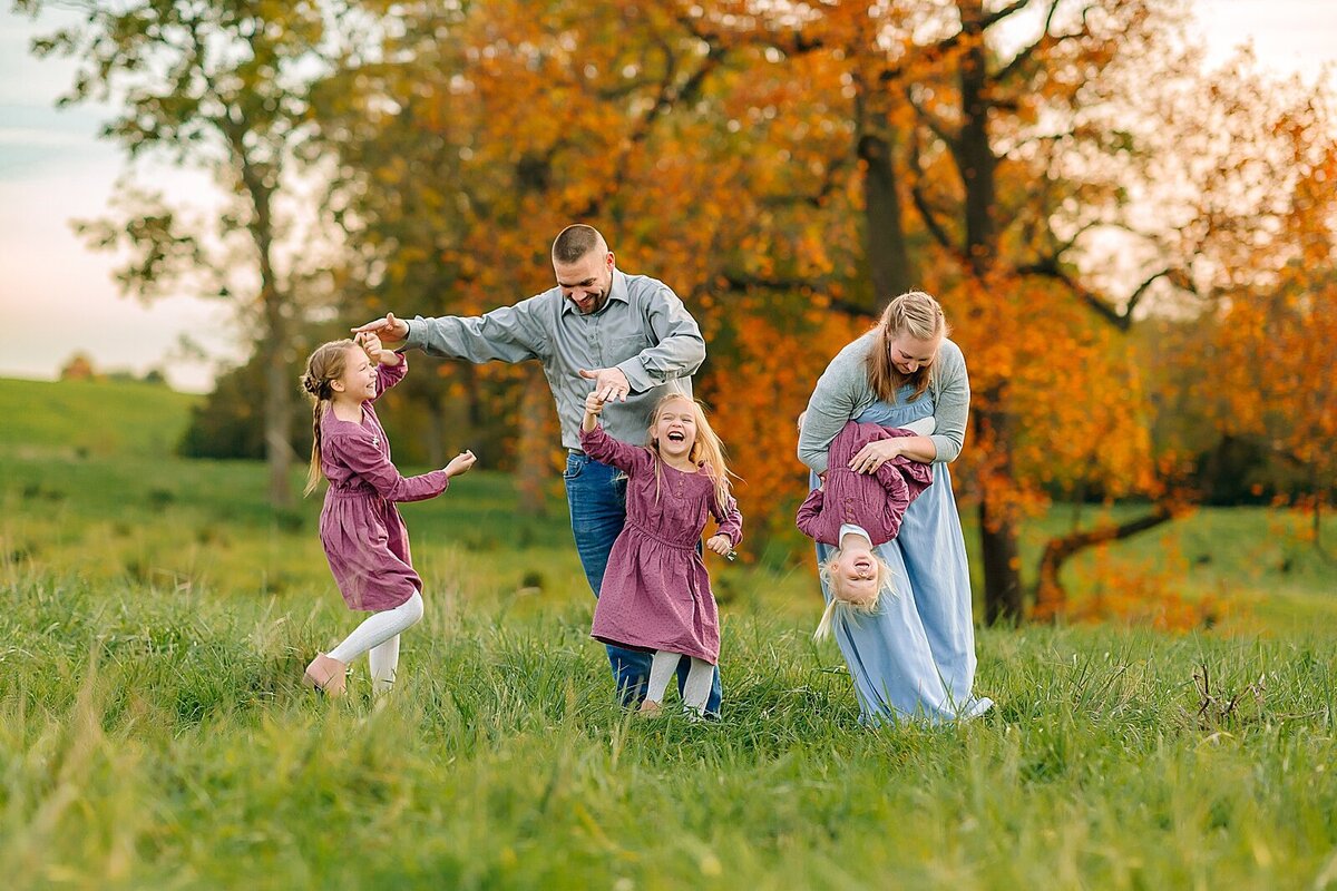 Mom and Dad with 3 daughters dancing in a field in the fall