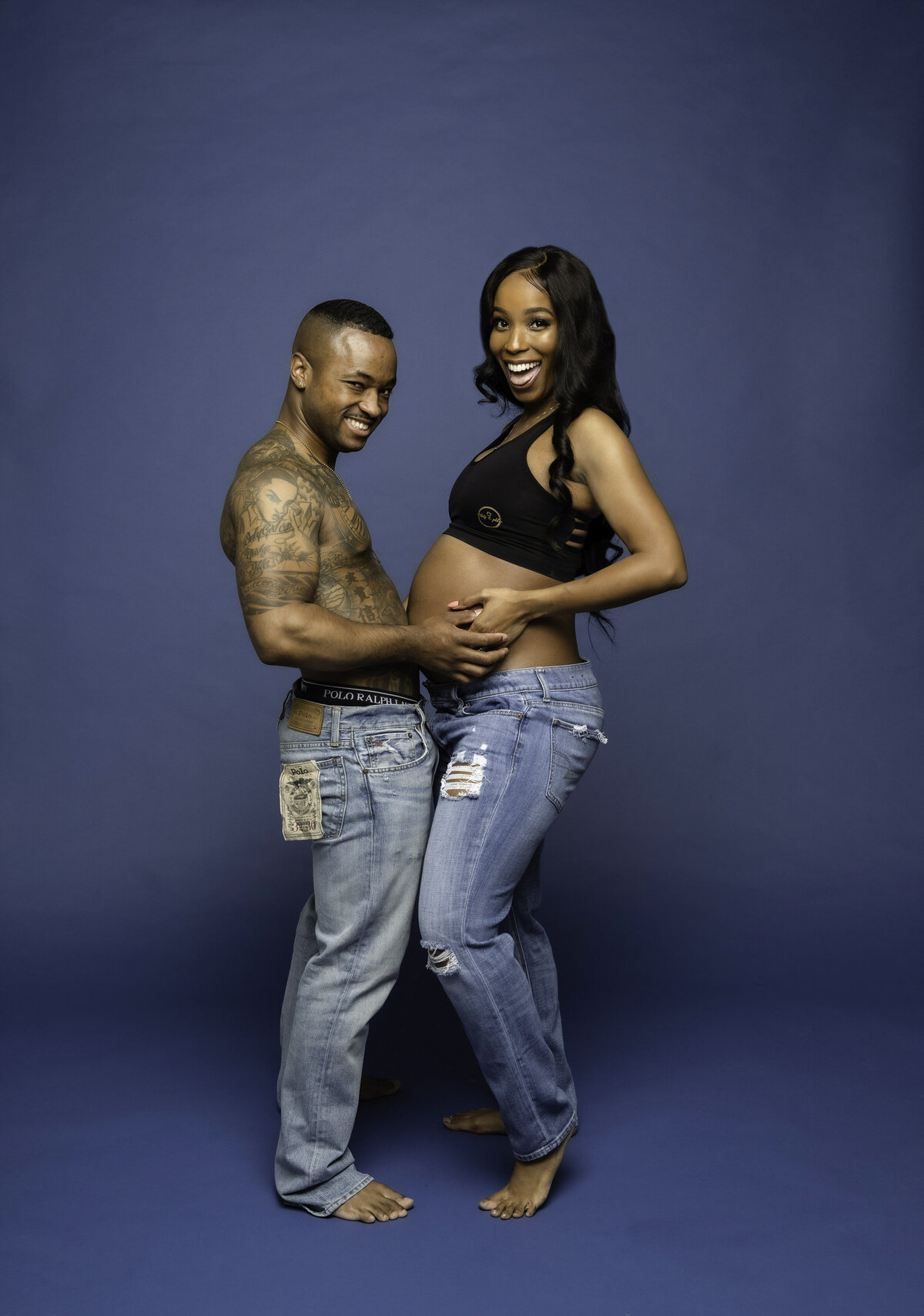 Black couple in blue jeans posing for maternity