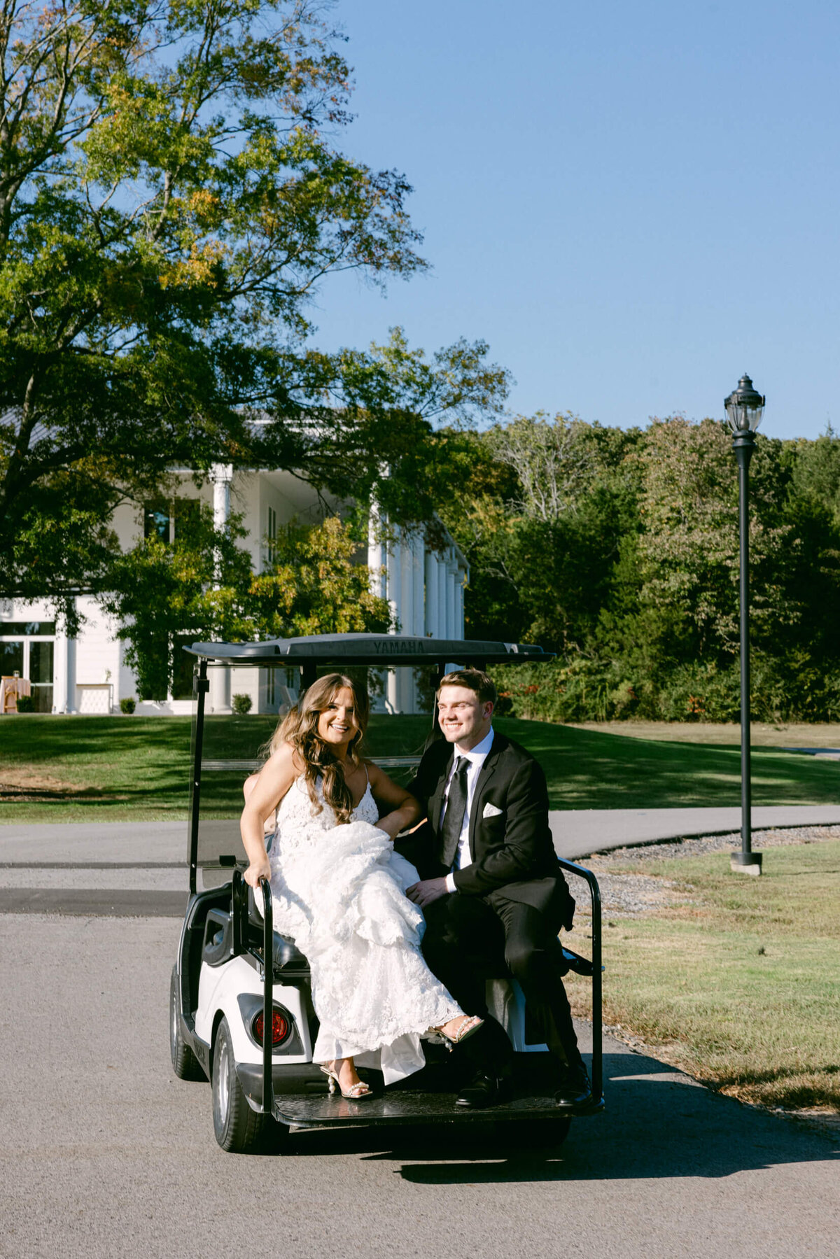 A wedding day photo of the bride and groom riding in the back of a golfcart