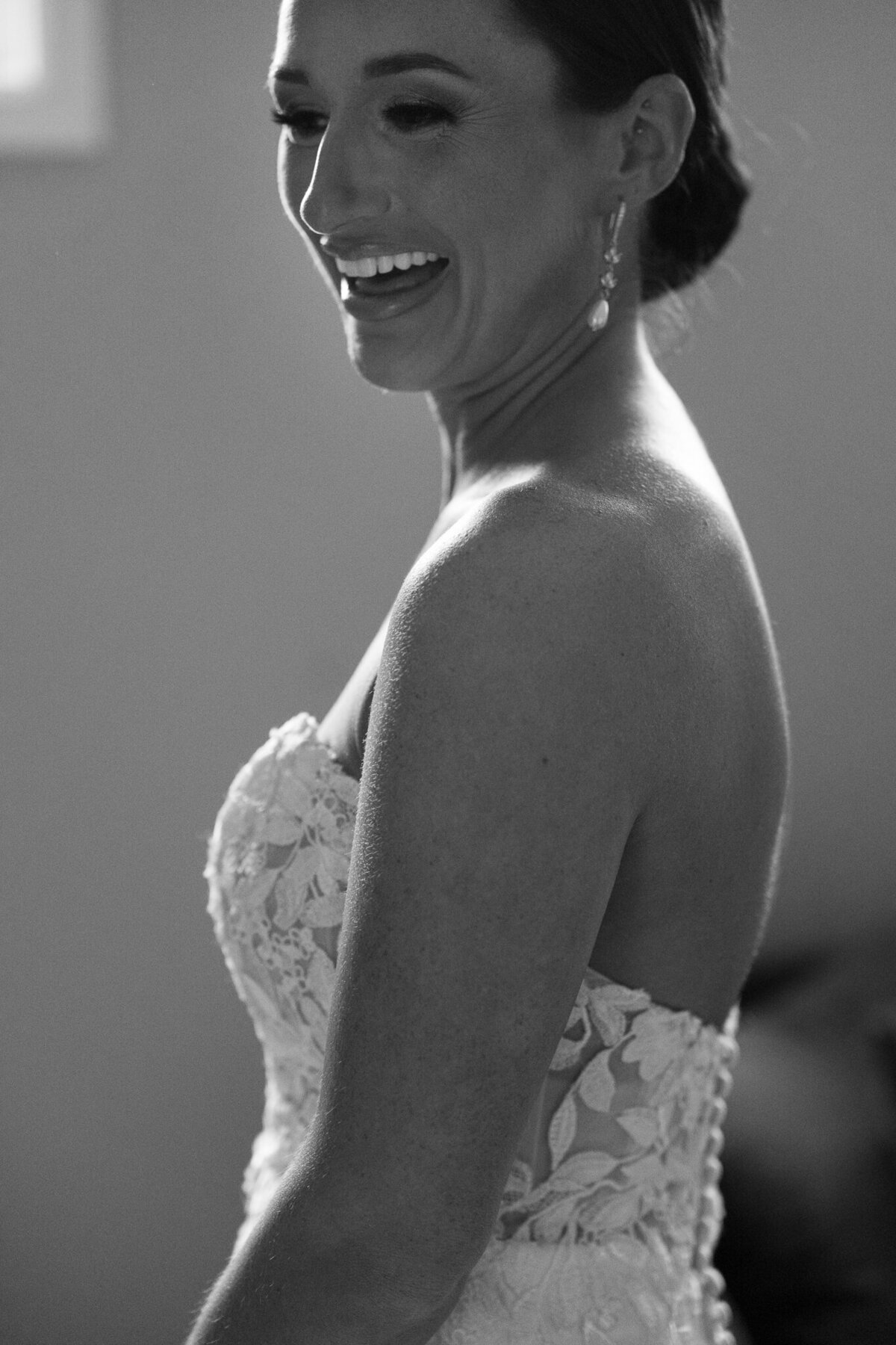 Candid black and white close-up of bride laughing in strapless lace gown