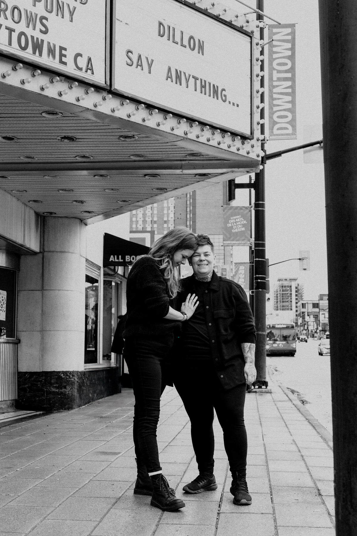 Black and white shot of an engagement portrait of a couple in front of Bytown Movie Theatre