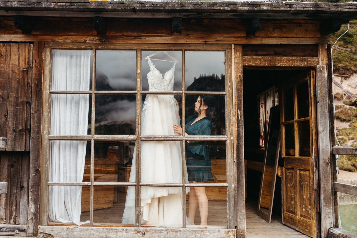 Wedding dress hanging in rustic cabin window