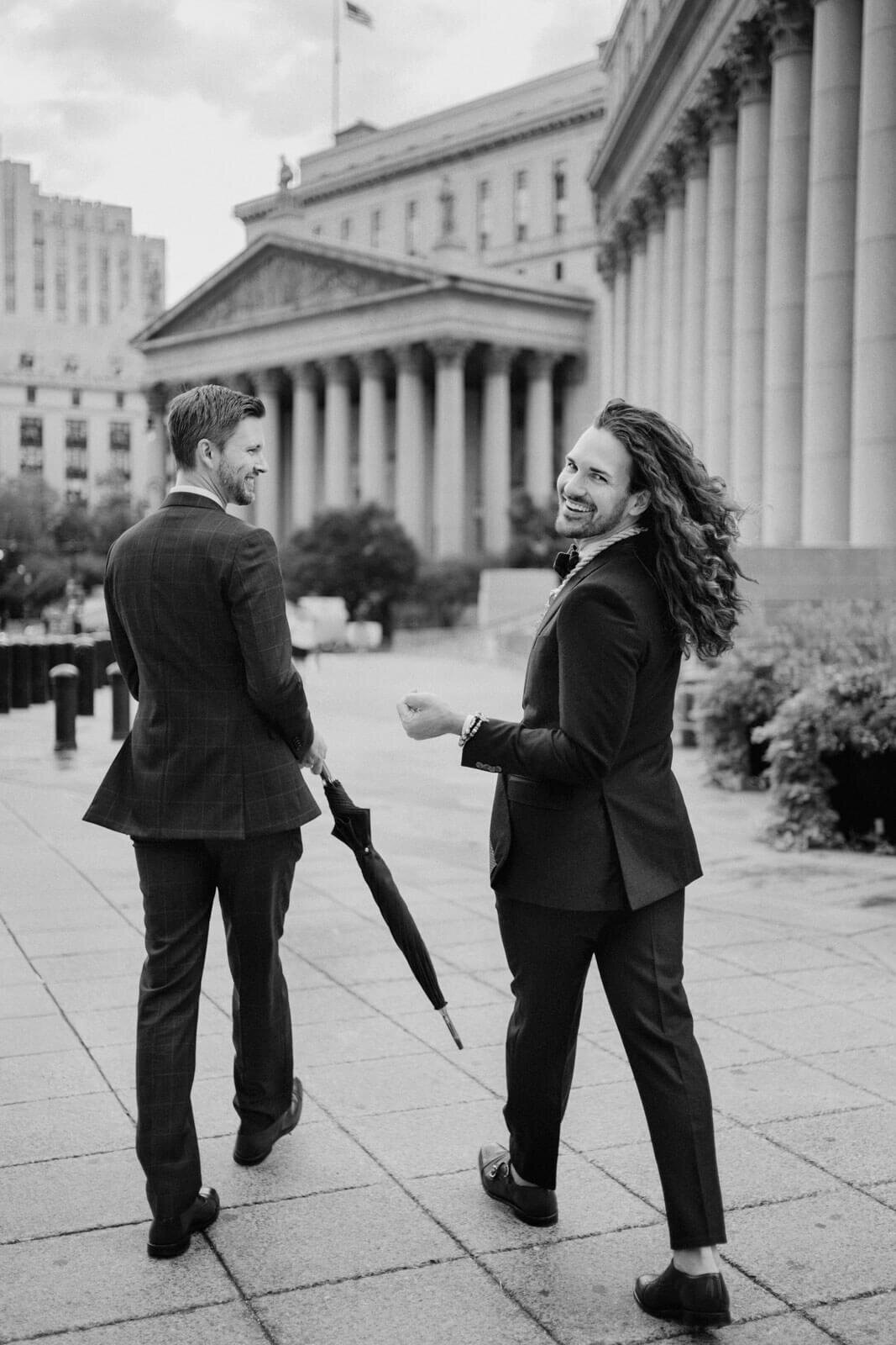 The two grooms are happily walking towards the NYC City Hall. Elopement Image by Jenny Fu Studio