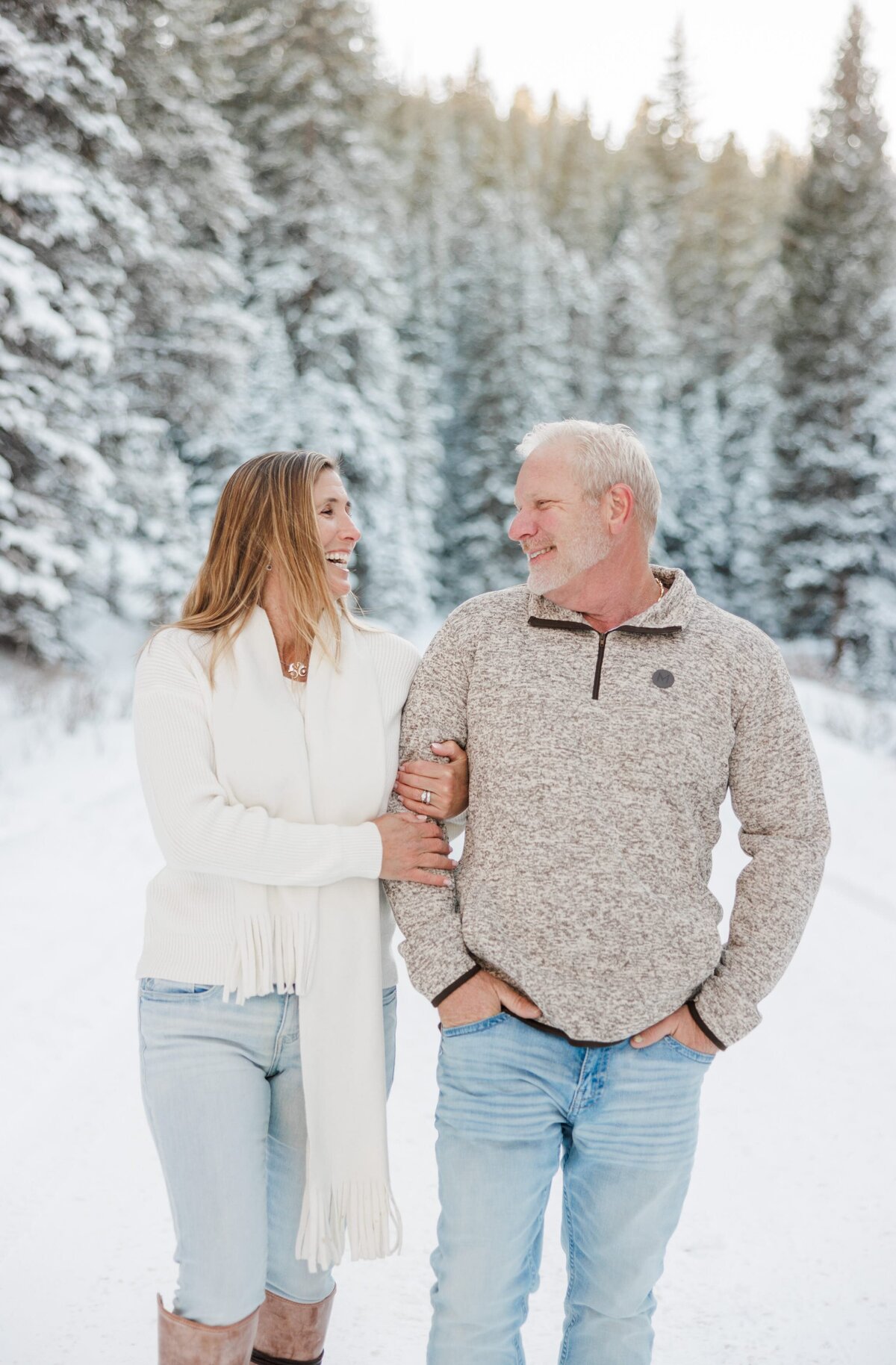 Happy mom and dad laugh at a joke while hiking in the snow