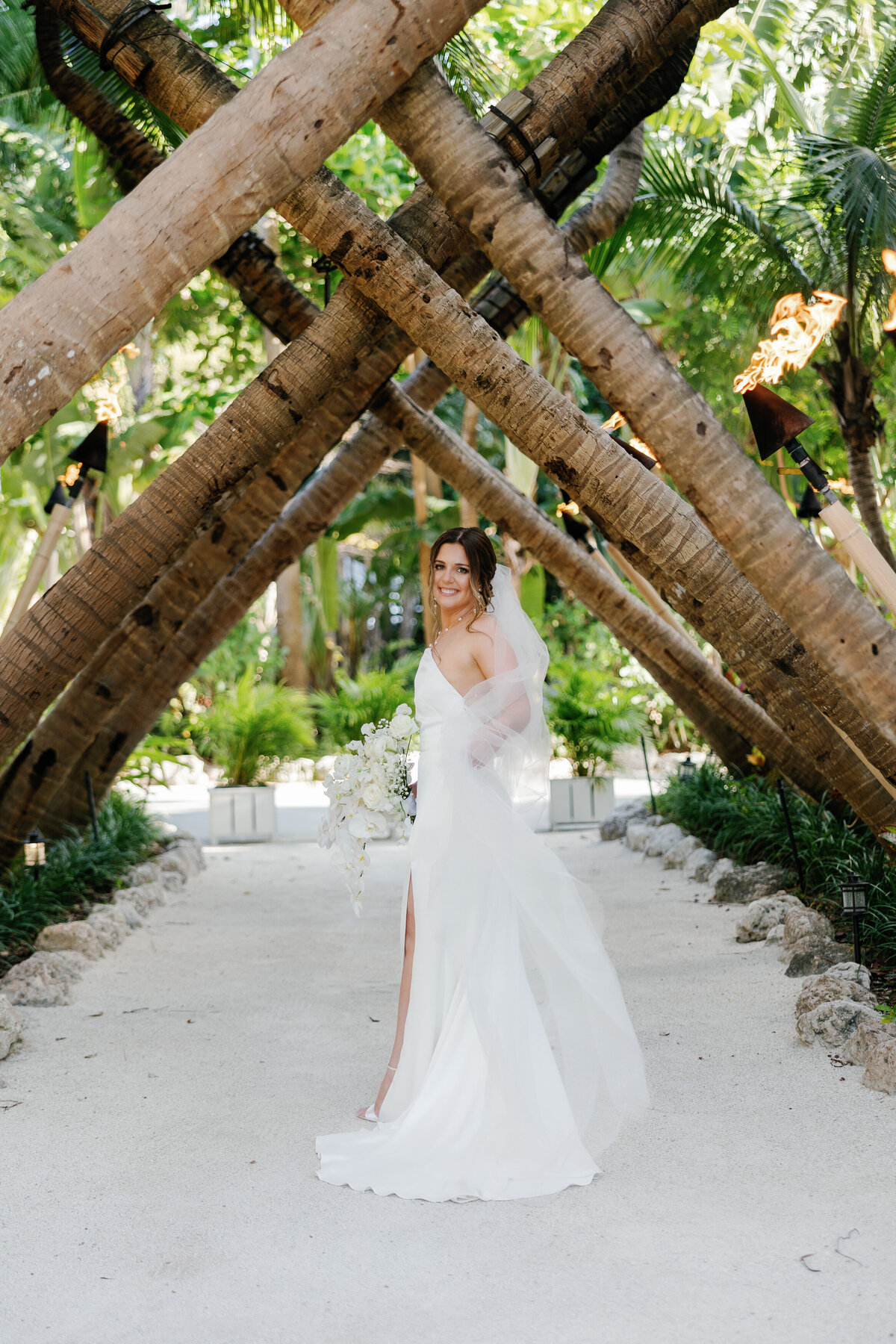 Bride standing under palm trees, captured by Miami wedding photographer Claudia Amalia, exemplifying her destination wedding photography in South Florida.