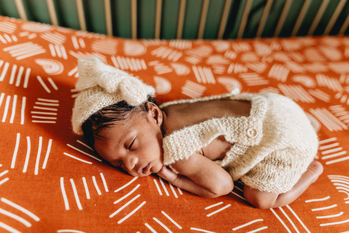 Infant photography session with newborn sleeping in a crib.