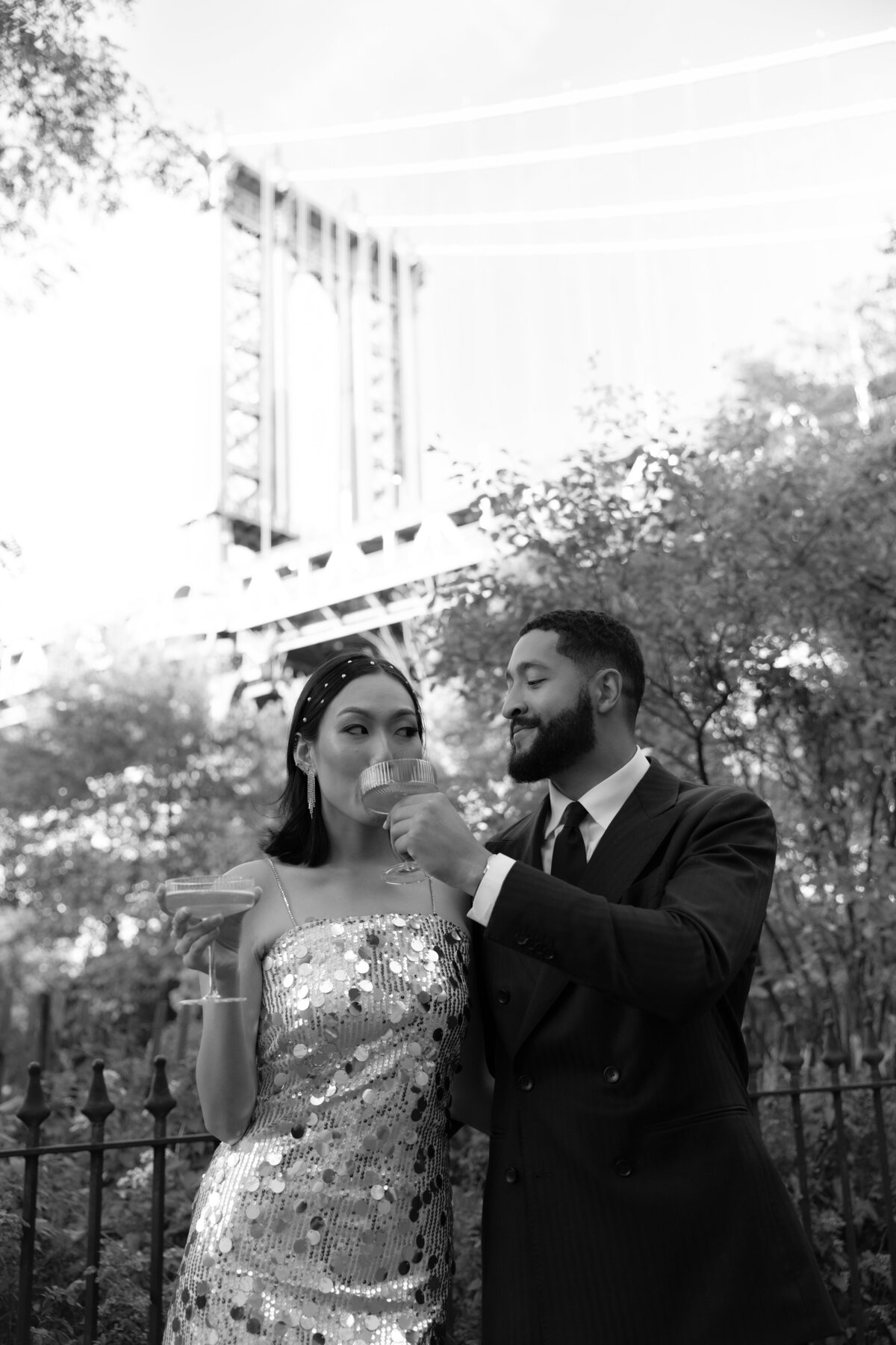The couple embraces near the base of the Brooklyn Bridge, surrounded by the DUMBO neighborhood's textures.