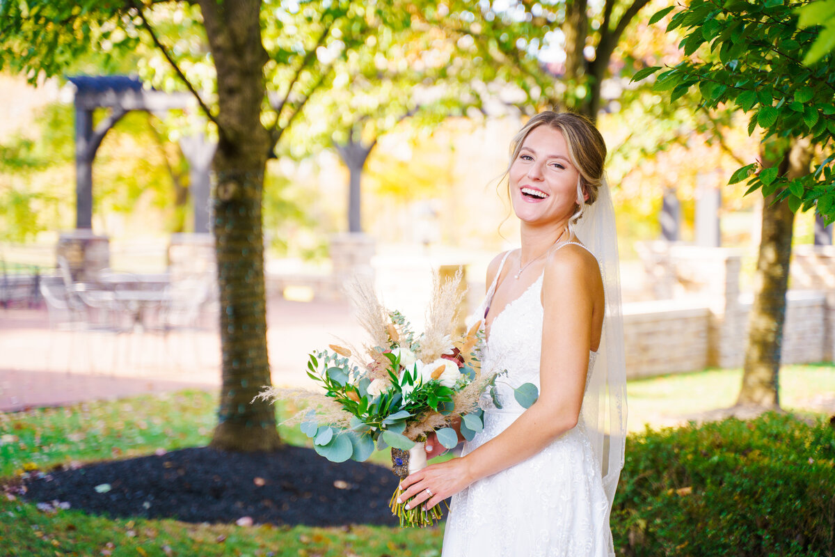 A beautiful bride holding her bouquet and laughing at her wedding at The Pinnacle Golf Course in Grove City, Ohio.