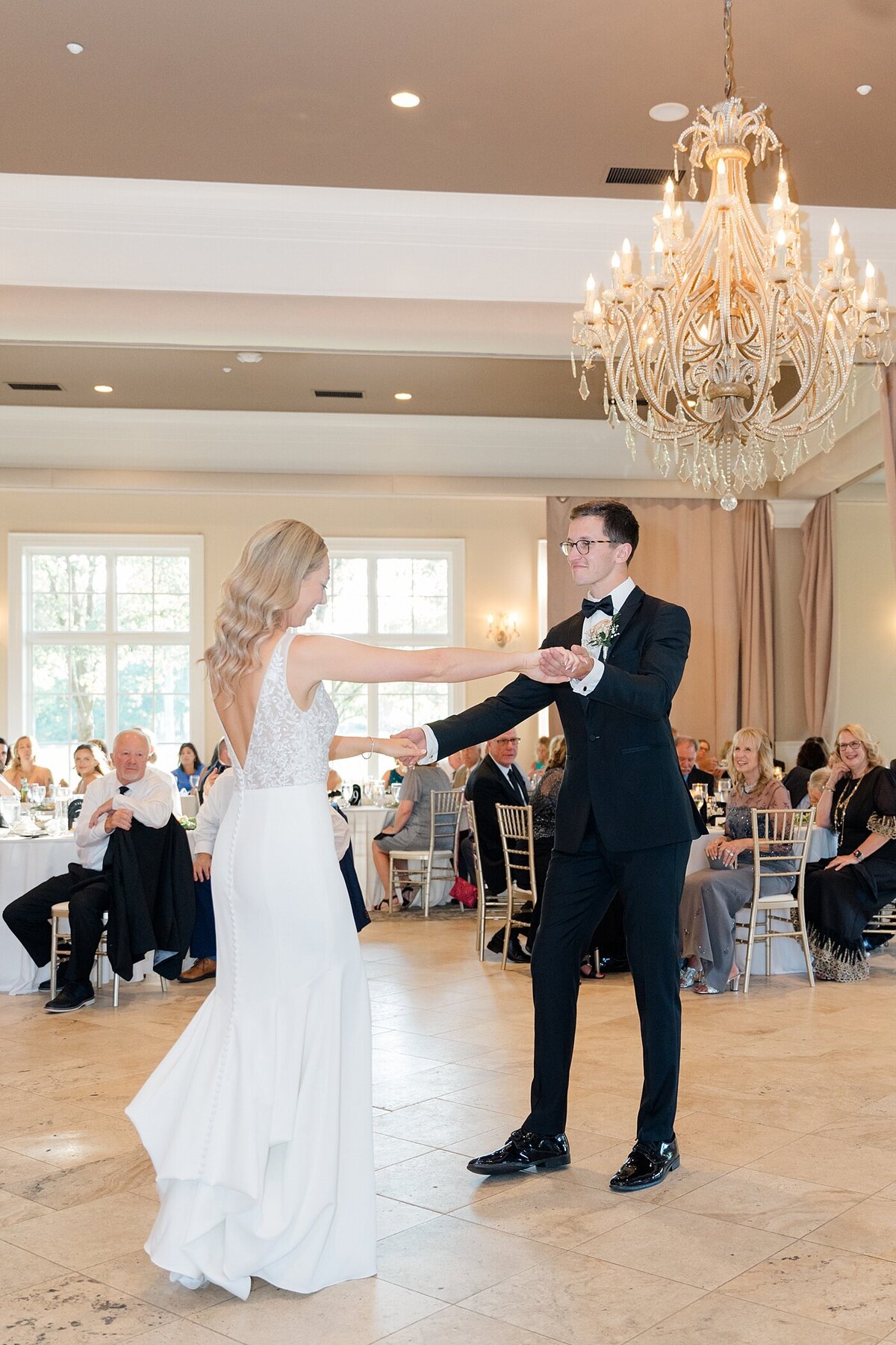 first dance between bride and groom at the Pinnacle gold club wedding reception space with large crystal chandeliers overhead