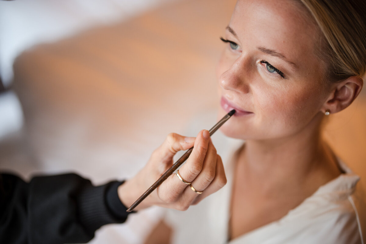 A bride gets her makeup done at a  Fairmount Park Horticulture Center wedding