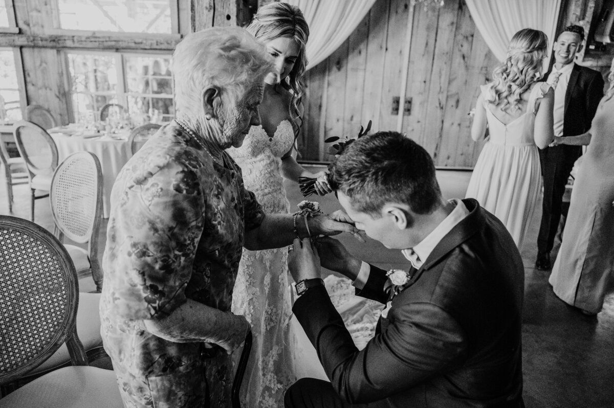 Groom is crouchin down near his gradmother