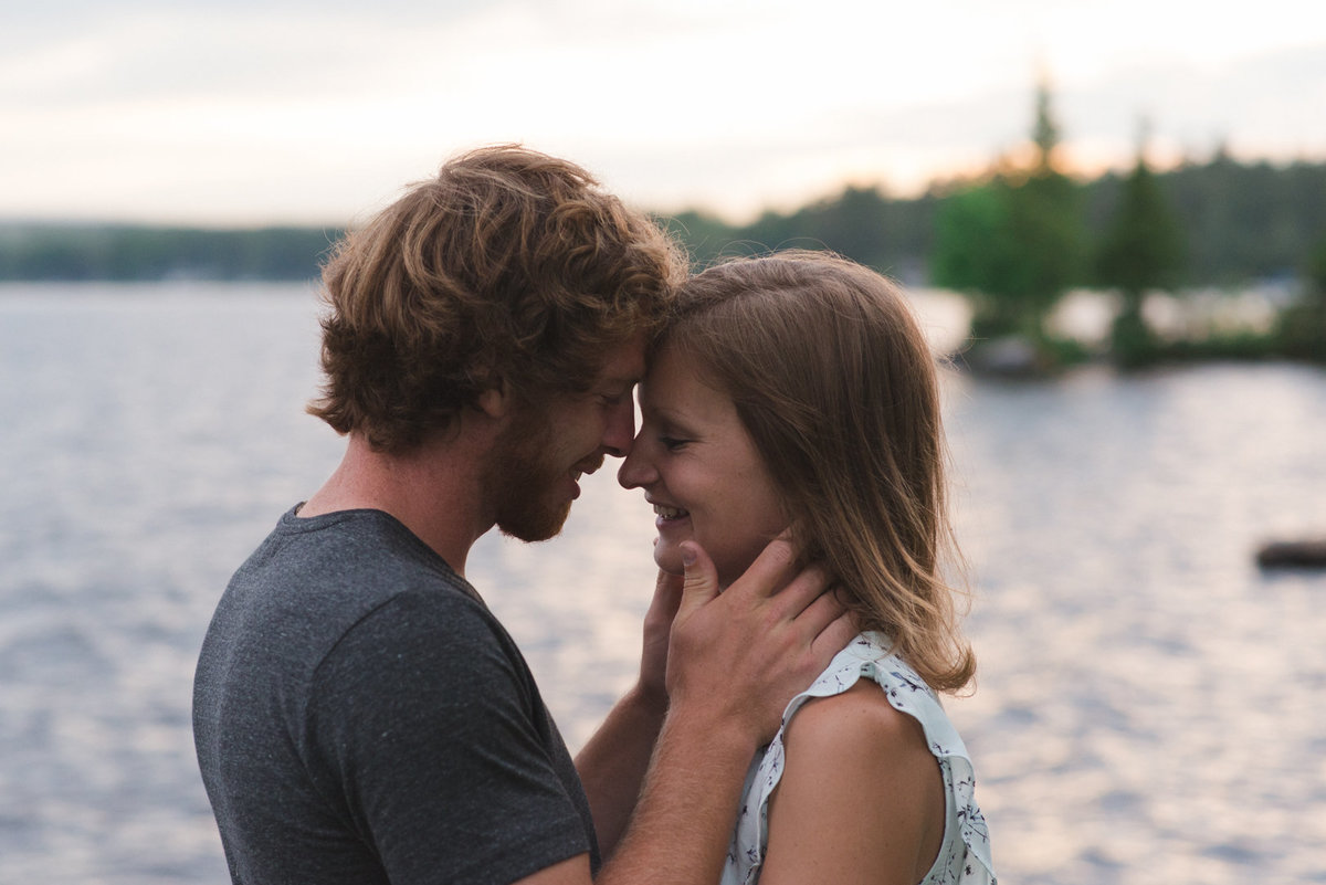 couple cuddling by the lake at sunset