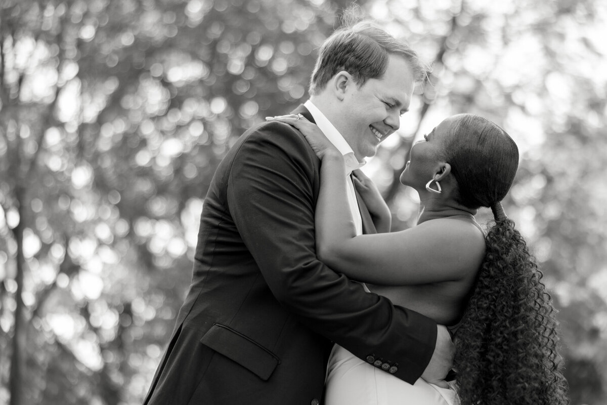 A couple shares a romantic moment in a formal garden along Michigan Avenue, surrounded by lush greenery and city charm.