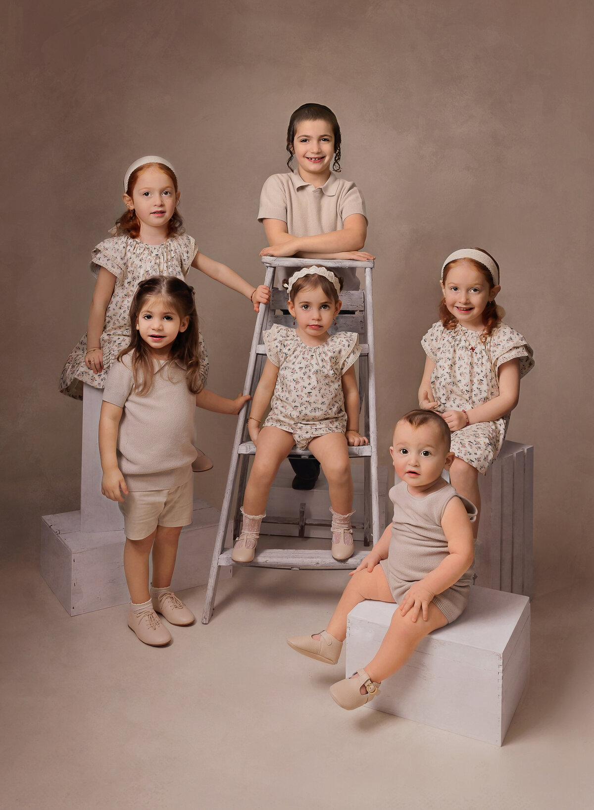 Six siblings pose for a brooklyn family photoshoot in a brooklyn studio. All siblings are smiling at the camera. Captured by Chaya Bornstein, Brooklyn Family Photographer