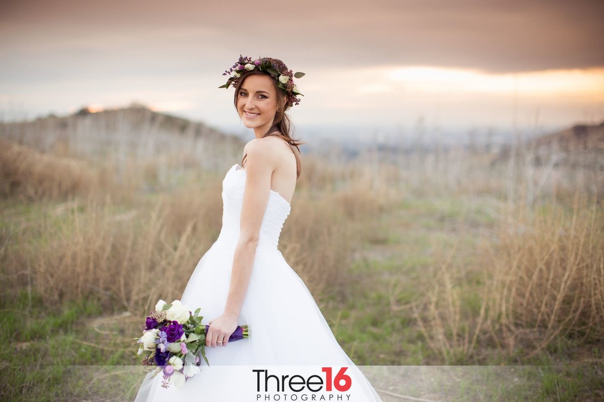 Bride smiles as she poses in the open field