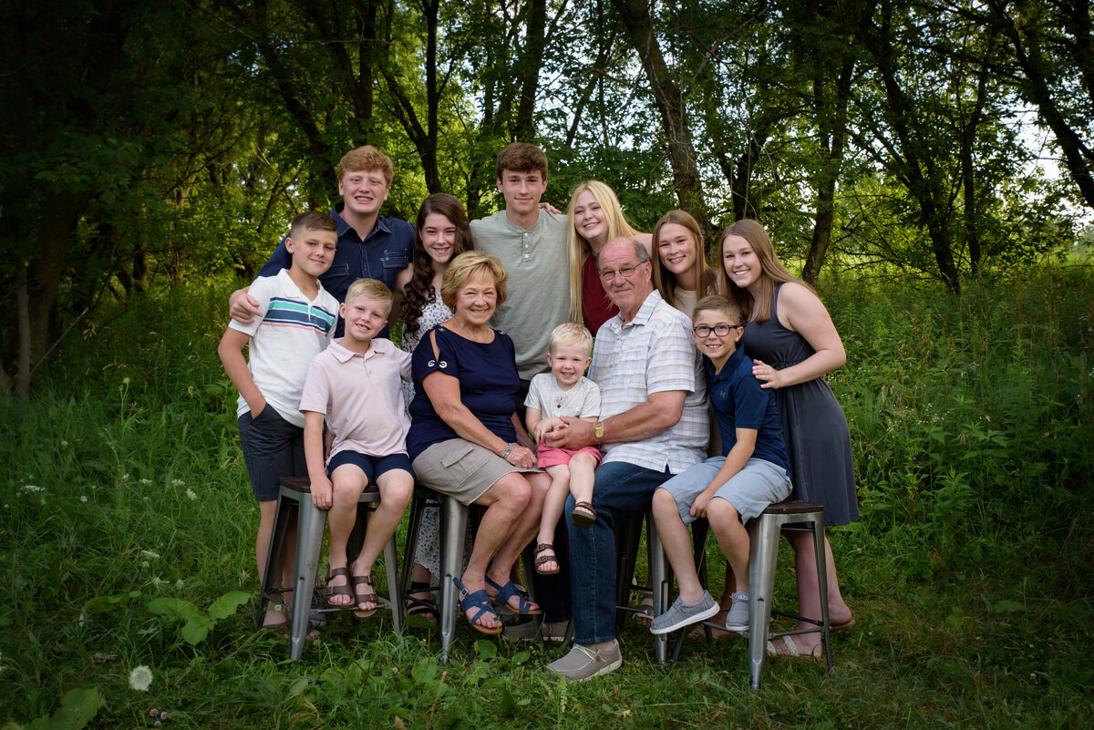 Large extended family portrait with grandparents and their grandchildren sitting in grassy area at Fonferek Glen County Park near Green Bay, Wisconsin