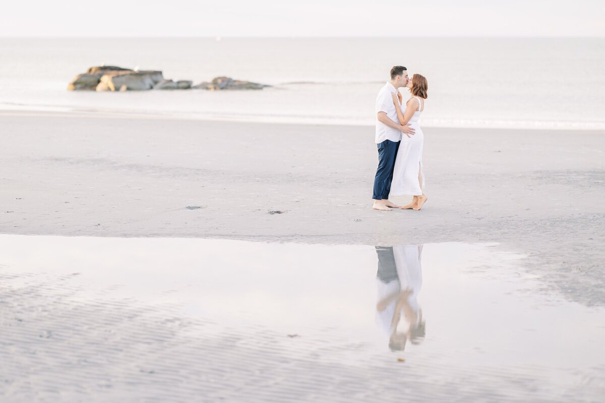 A couple kissing on Wingaersheek Beach during their engagement photo session.