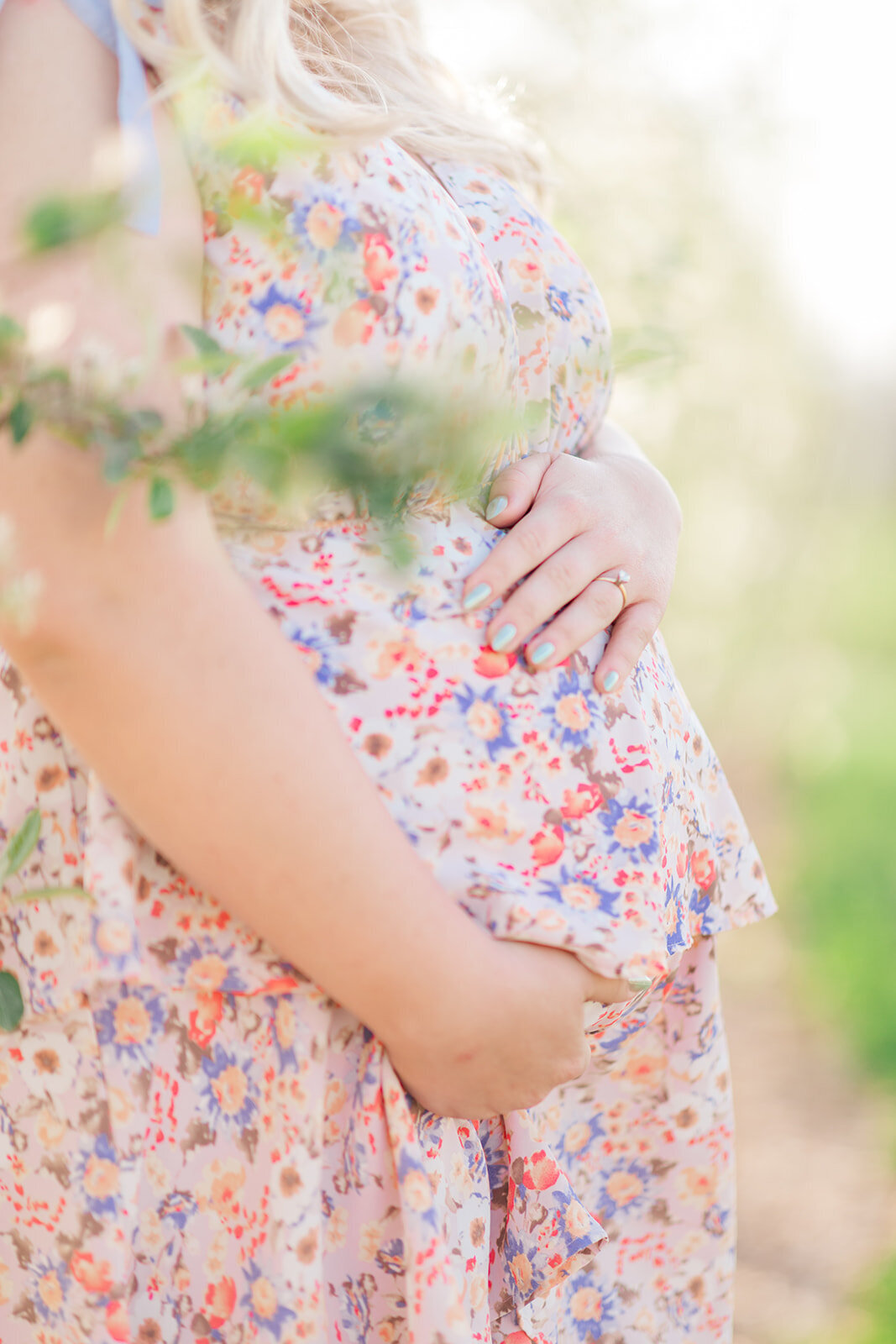 Pregnant mother in flowy dress standing among orchard rows