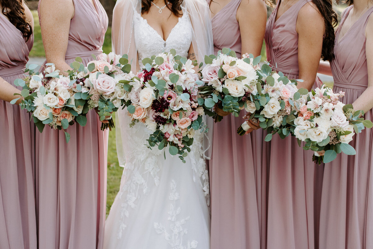 bride and bridesmaids all holding bouquets of flowers
