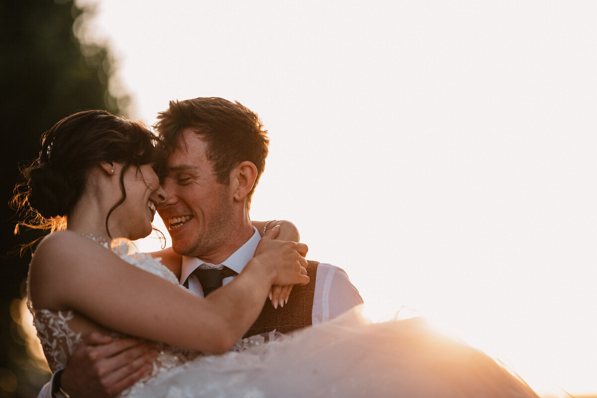 Bride and groom sharing a joyful, romantic moment at sunset during their wedding at Danby Castle in Whitby, a luxury countryside venue